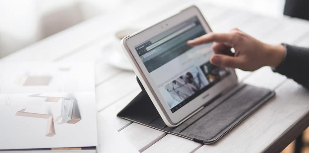 Jemand berührt ein Tablet über das eine digitale Ebene schwebt mit unterschiedlichen Grafiken zu digitalem und print Marketing