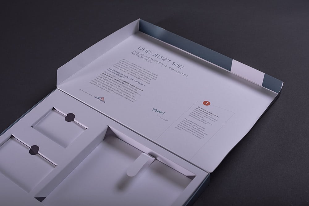 Eine aufgeklappte Box mit Aussparungen drei verscheidene Produkte