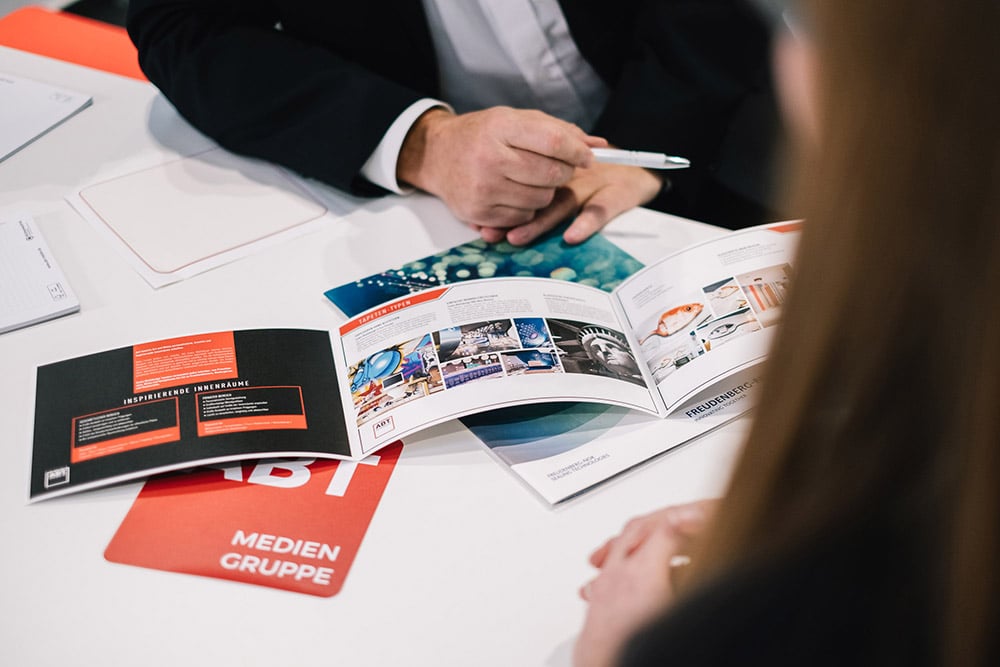 hochwertige und veredelt gedruckte Flyer liegen auf einem Tisch und werden präsentiert