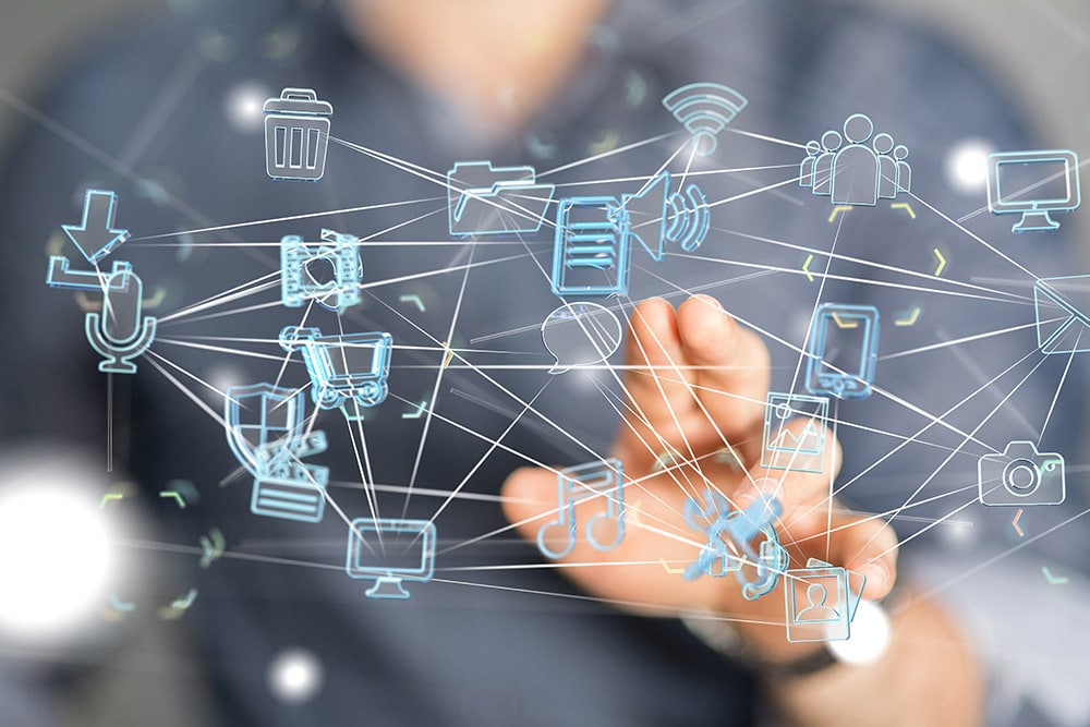 Im Hintergrund ist sehr schwammig eine Person zu erkennen, die eine Hand austreckt und im Vordergrund ist eine Vernetzung von transparenten Icons und Grafiken zu Daten, Tablets, Warenkörben und Einkaufrsprozessen zu sehen