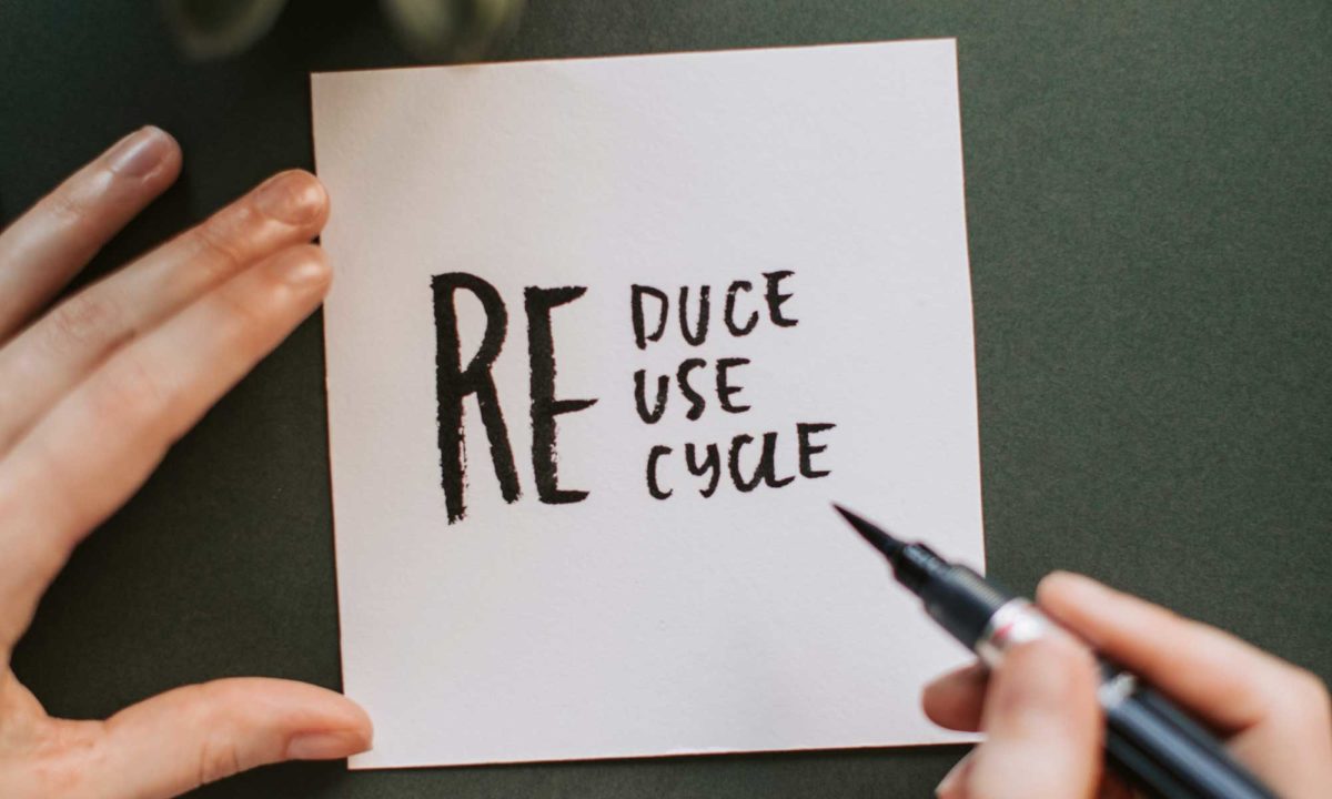 Auf Papier wird mti einem schwarzen Stift "RE-duce,-use,-cycle" geschrieben
